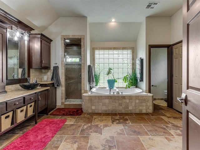 9408 S Caldwell Dr, Midwest City, OK 73130 - bathroom featuring toilet, a stall shower, a bath, vanity, and stone tile flooring