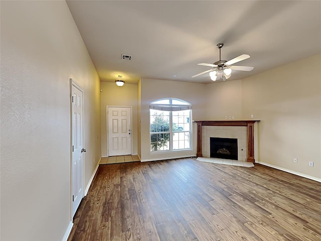 unfurnished living room with baseboards, a fireplace, ceiling fan, and wood finished floors
