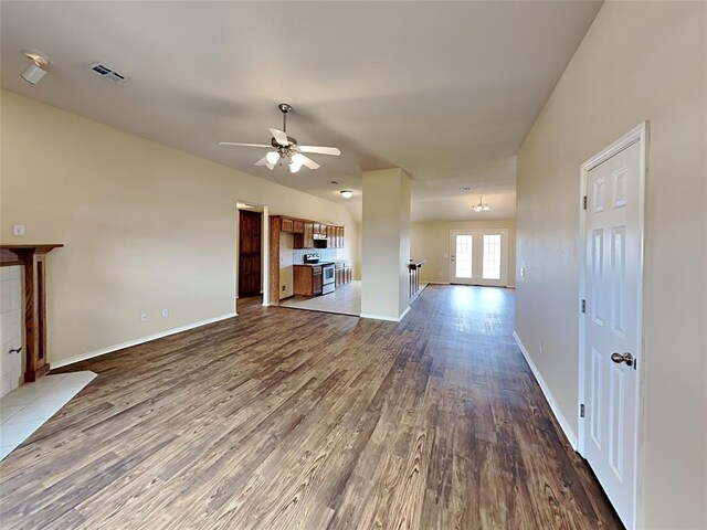 unfurnished living room with baseboards, visible vents, wood finished floors, and a ceiling fan