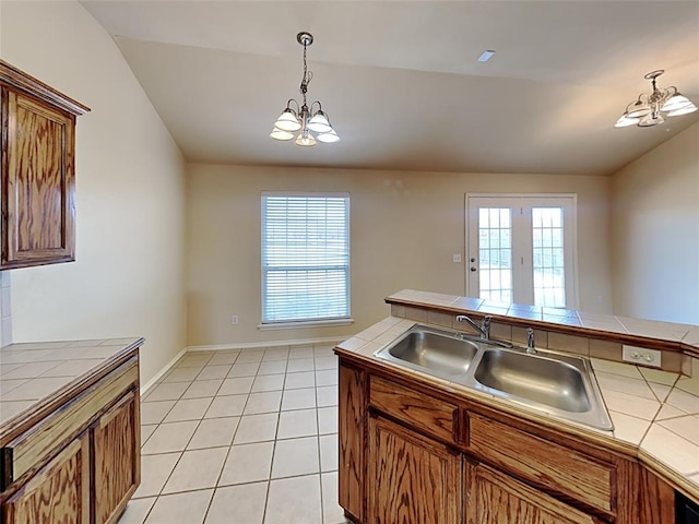 kitchen with tile counters, hanging light fixtures, a chandelier, and a sink