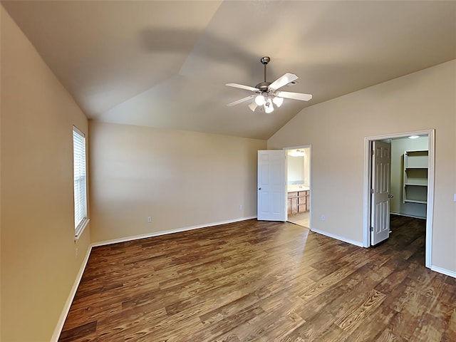 unfurnished bedroom with lofted ceiling, baseboards, and dark wood-style floors
