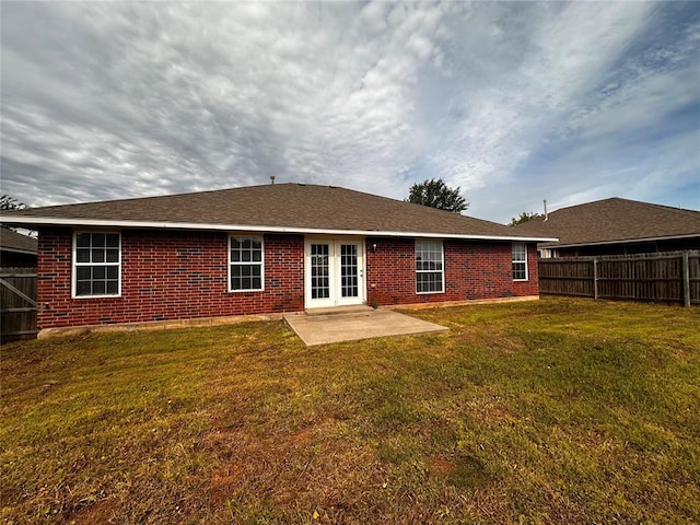 rear view of property featuring french doors, a yard, a fenced backyard, brick siding, and a patio area