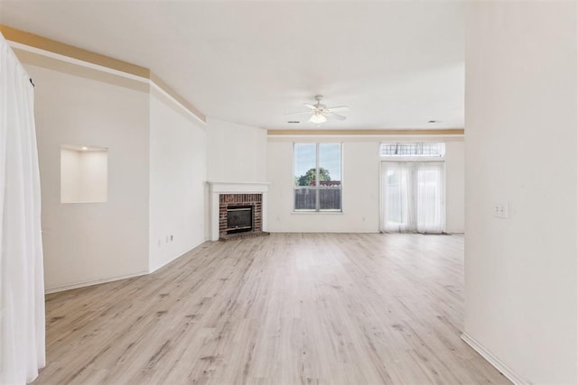 unfurnished living room with wood finished floors, a ceiling fan, and a brick fireplace