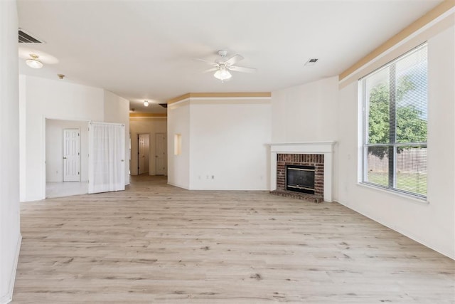 unfurnished living room featuring a fireplace, a ceiling fan, visible vents, and light wood-style floors