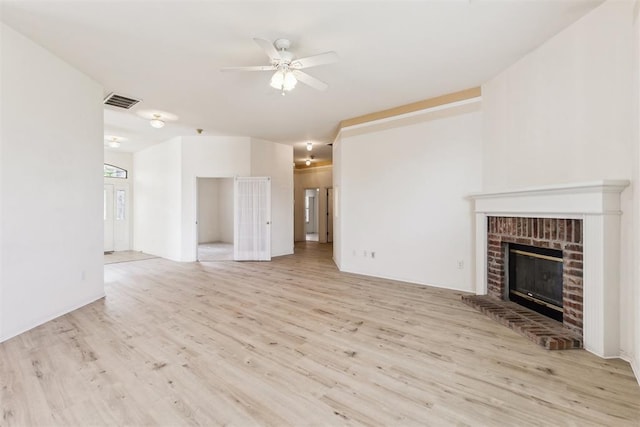 unfurnished living room featuring light wood-style floors, visible vents, ceiling fan, and a brick fireplace