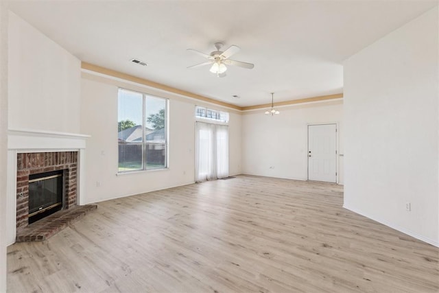 unfurnished living room featuring a brick fireplace, visible vents, baseboards, ceiling fan, and light wood-style floors