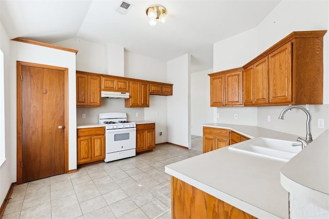 kitchen with under cabinet range hood, white gas range, and brown cabinetry