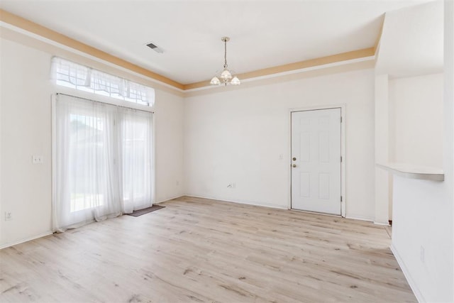 unfurnished room featuring baseboards, light wood finished floors, and an inviting chandelier
