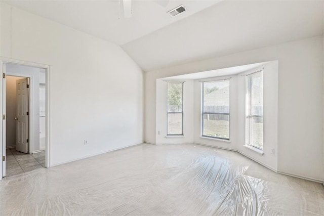 unfurnished room featuring a ceiling fan, visible vents, baseboards, and lofted ceiling