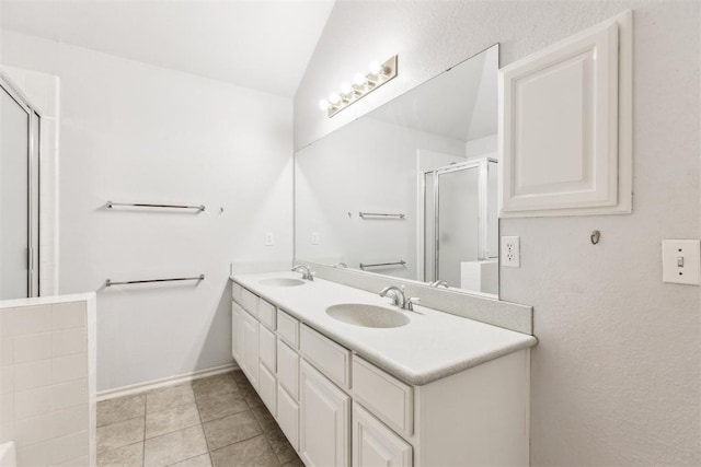full bath featuring a sink, double vanity, a stall shower, and tile patterned flooring