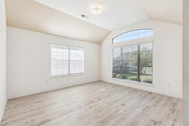 empty room with lofted ceiling, visible vents, and wood finished floors