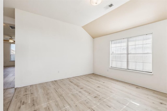 unfurnished room featuring vaulted ceiling, light wood-style floors, visible vents, and a ceiling fan