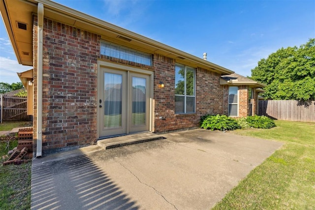exterior space featuring brick siding, fence, and a patio area