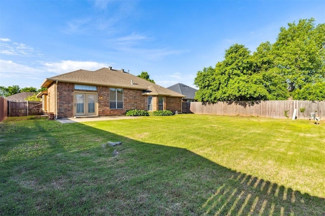 back of house with a lawn, brick siding, french doors, a patio area, and a fenced backyard