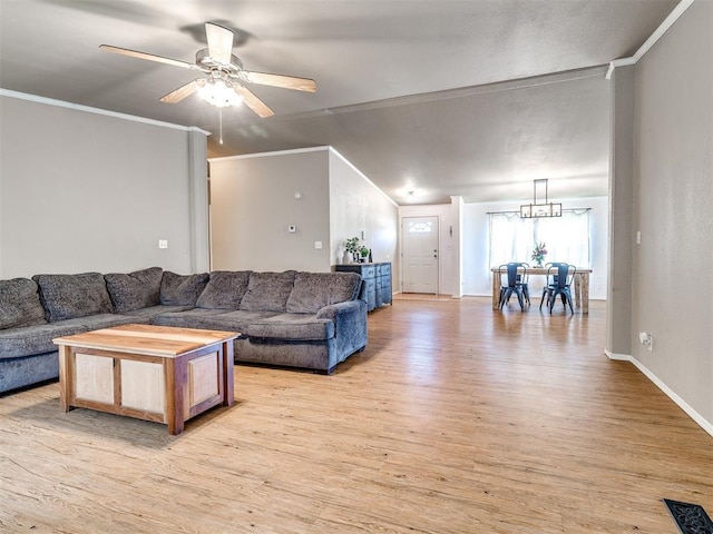 living room featuring baseboards, visible vents, ceiling fan with notable chandelier, crown molding, and light wood-type flooring