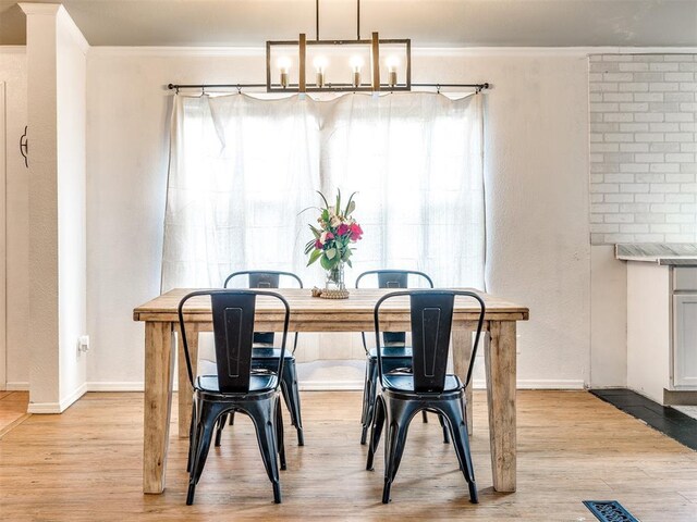 dining room with light wood-type flooring, baseboards, and crown molding