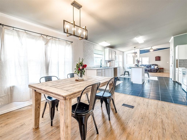 dining area with visible vents, ceiling fan with notable chandelier, and wood finished floors