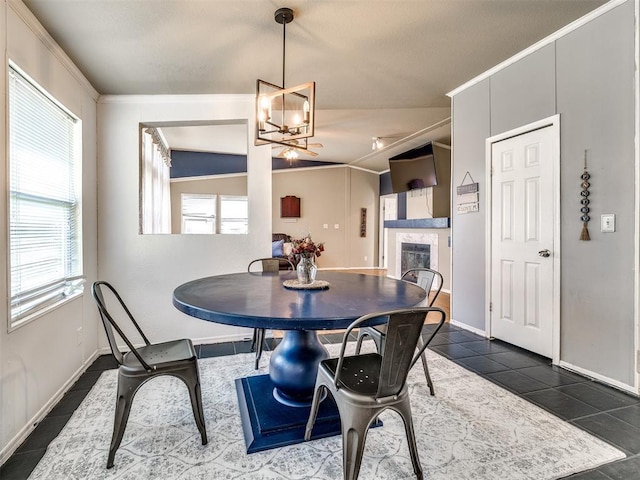 dining space with a wealth of natural light, dark tile patterned flooring, a fireplace, and a notable chandelier