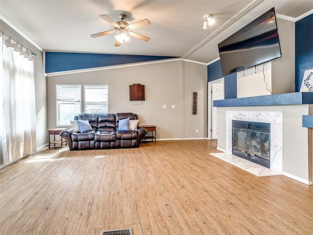 living area with wood finished floors, ornamental molding, vaulted ceiling, a ceiling fan, and baseboards