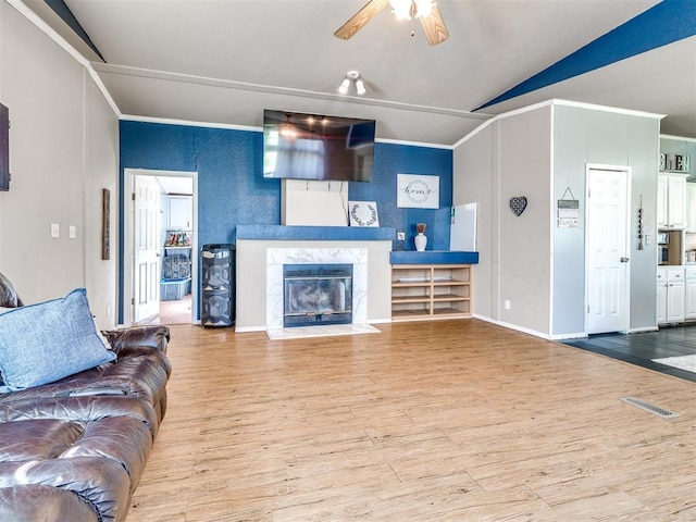living area with a ceiling fan, lofted ceiling, a high end fireplace, and wood finished floors