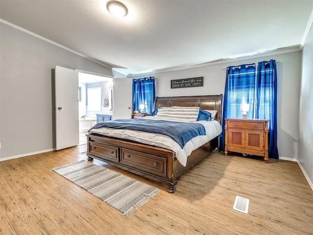 bedroom with lofted ceiling, visible vents, crown molding, light wood finished floors, and baseboards