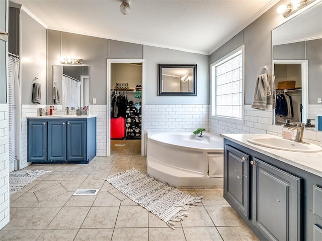 bathroom featuring tile walls, ornamental molding, a sink, tile patterned floors, and vaulted ceiling