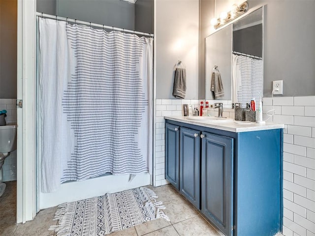 full bathroom with tile patterned floors, tile walls, vanity, and wainscoting