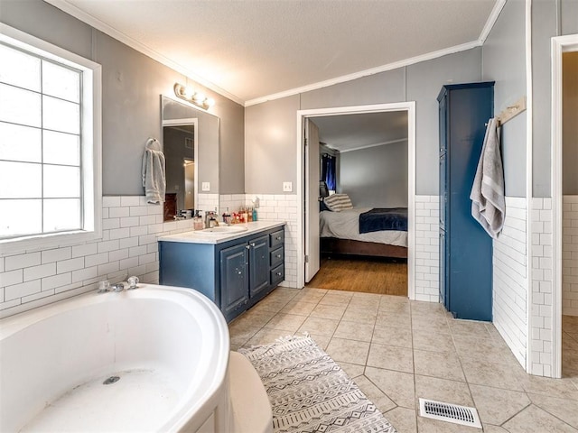 bathroom featuring tile walls, a wainscoted wall, vanity, visible vents, and tile patterned flooring