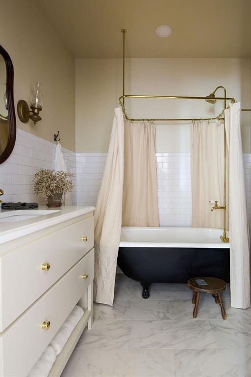 1801 N Broadway Ave, Shawnee, OK 74804 - bathroom featuring tile walls, marble finish floor, vanity, shower / tub combo with curtain, and wainscoting