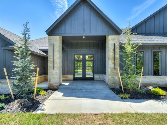 entrance to property featuring french doors, board and batten siding, a shingled roof, and stone siding