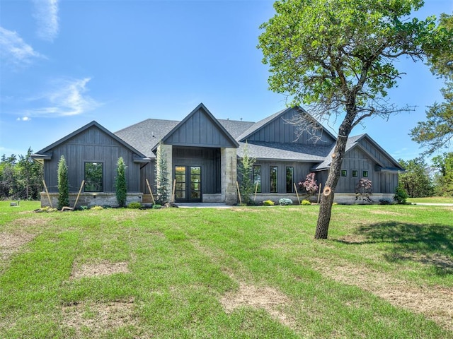 view of front of home featuring a front yard, board and batten siding, french doors, and roof with shingles