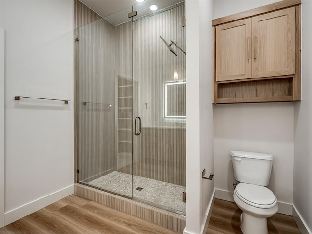 bathroom featuring wood finished floors, a shower stall, and baseboards