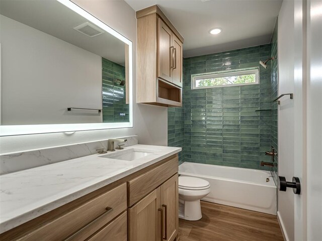 bathroom with toilet, wood finished floors, shower / bath combination, and vanity