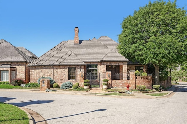 368 Millbrook Dr, Norman, OK 73072 - view of front of property with brick siding, a chimney, fence, and a tile roof