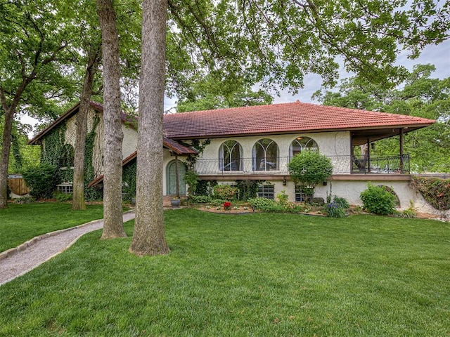 view of front of house with a front lawn, stucco siding, and a tile roof