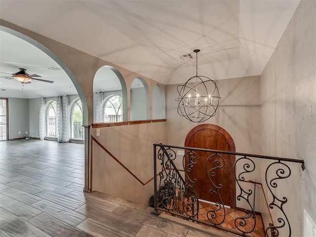 staircase with a chandelier and ceiling fan