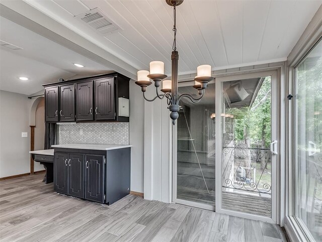 kitchen with light countertops, tasteful backsplash, baseboards, pendant lighting, and light wood-style flooring