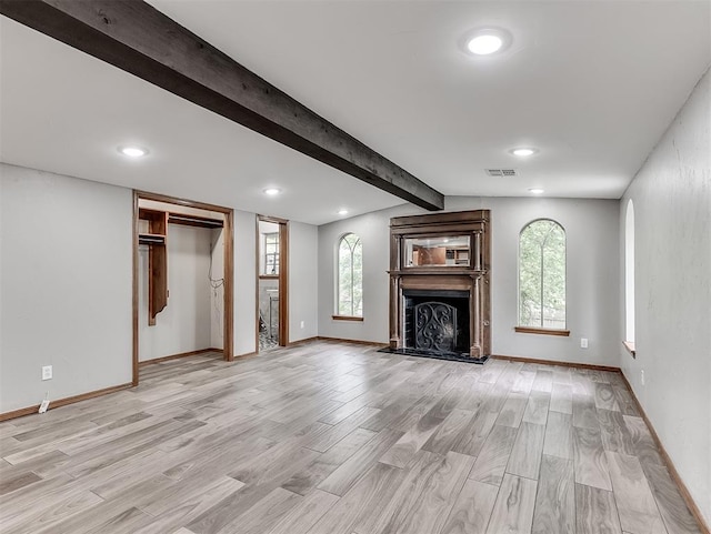unfurnished living room with light wood-style flooring, a fireplace with raised hearth, beamed ceiling, baseboards, and recessed lighting