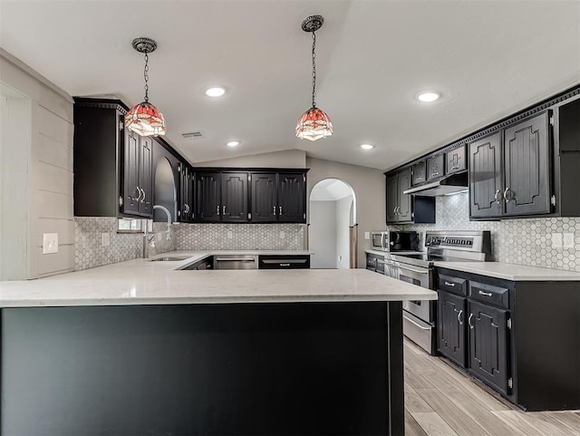 kitchen with appliances with stainless steel finishes, arched walkways, tasteful backsplash, lofted ceiling, and recessed lighting