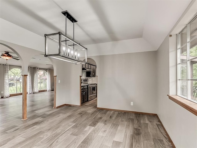 unfurnished living room with arched walkways, healthy amount of natural light, and light wood-type flooring