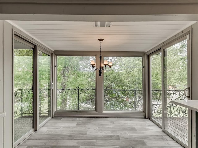 unfurnished sunroom featuring a chandelier and wood finished floors