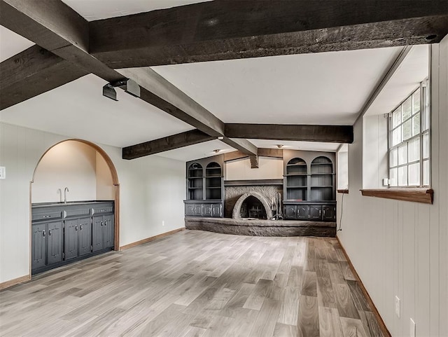 unfurnished living room with beam ceiling, a fireplace, and wood finished floors