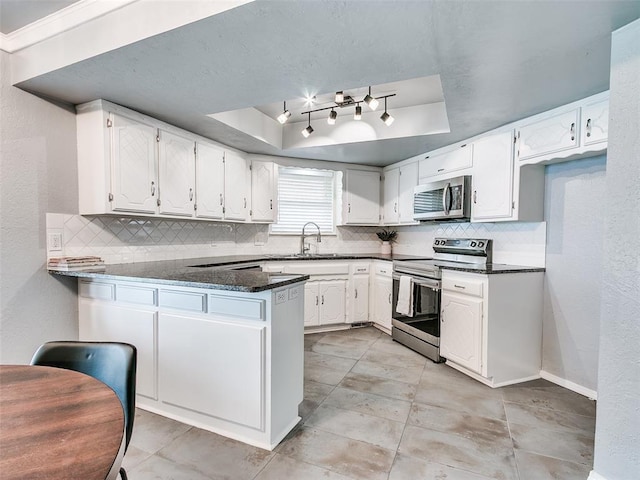 7700 Wegner Way, Oklahoma City, OK 73162 - kitchen featuring appliances with stainless steel finishes, a raised ceiling, tasteful backsplash, a peninsula, and a textured wall