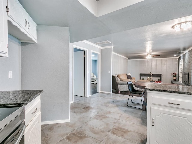 7700 Wegner Way, Oklahoma City, OK 73162 - kitchen with baseboards, ceiling fan, dark stone counters, white cabinetry, and a textured wall