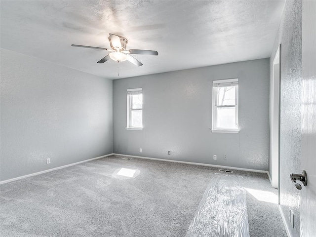 7700 Wegner Way, Oklahoma City, OK 73162 - unfurnished room with healthy amount of natural light, a ceiling fan, baseboards, carpet floors, and a textured wall
