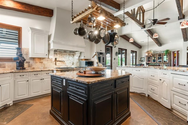 9639 Horizon Cir, Sperry, OK 74073 - kitchen featuring dark cabinetry, beamed ceiling, finished concrete flooring, and custom range hood