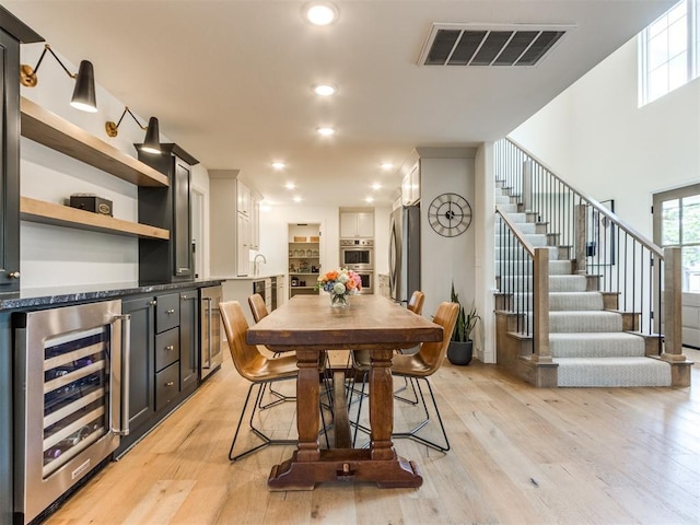 11825 Leaning Elm Rd, Oklahoma City, OK 73120 - dining area featuring wine cooler, light wood-style flooring, stairway, and recessed lighting