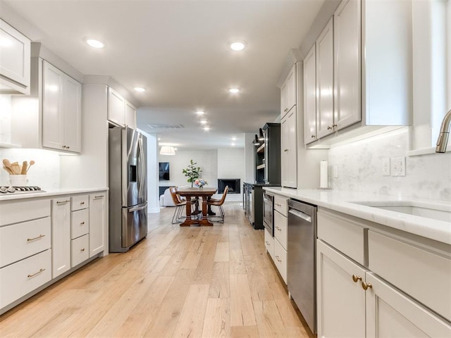 11825 Leaning Elm Rd, Oklahoma City, OK 73120 - kitchen with appliances with stainless steel finishes, light wood-type flooring, open floor plan, recessed lighting, and white cabinetry