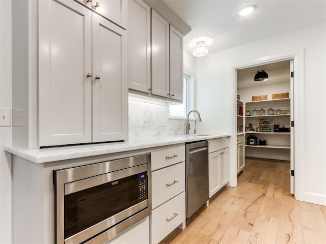 11825 Leaning Elm Rd, Oklahoma City, OK 73120 - kitchen featuring stainless steel appliances, light wood-type flooring, light countertops, backsplash, and white cabinetry