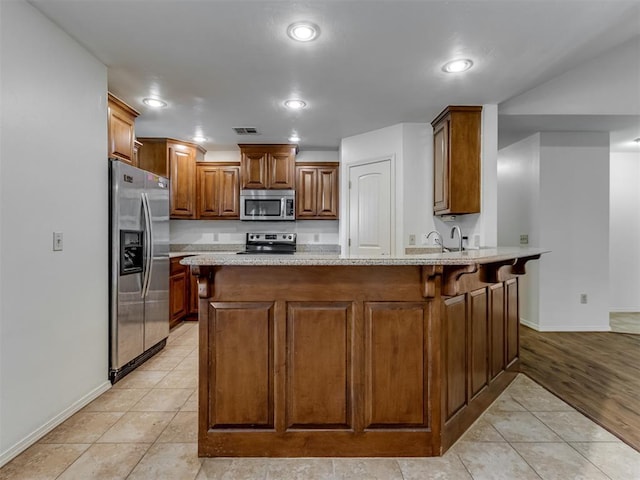20140 N Rolling Meadows Dr, Luther, OK 73054 - kitchen featuring appliances with stainless steel finishes, a peninsula, baseboards, light tile patterned floors, and brown cabinets